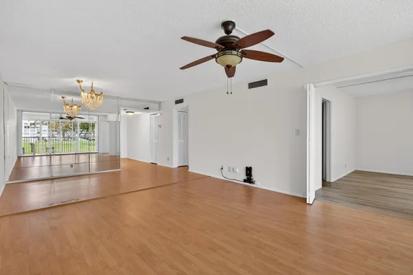 a view of empty room with wooden floor and fan