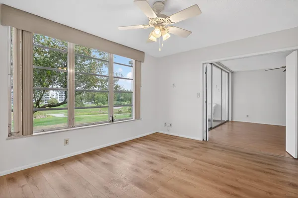 a view of an empty room with a window and wooden floor