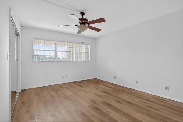 a view of empty room with wooden floor and fan