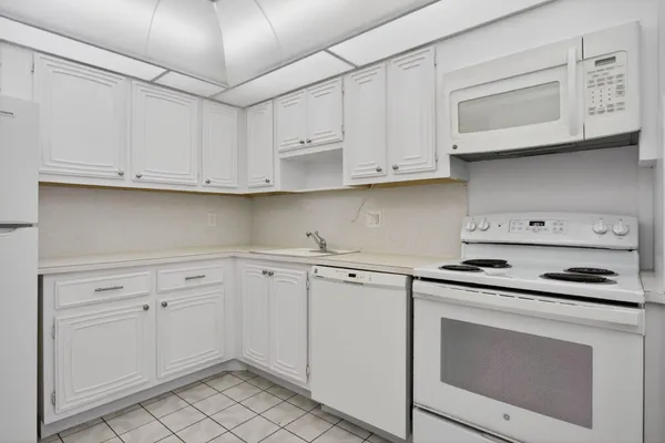 a kitchen with white cabinets and white appliances