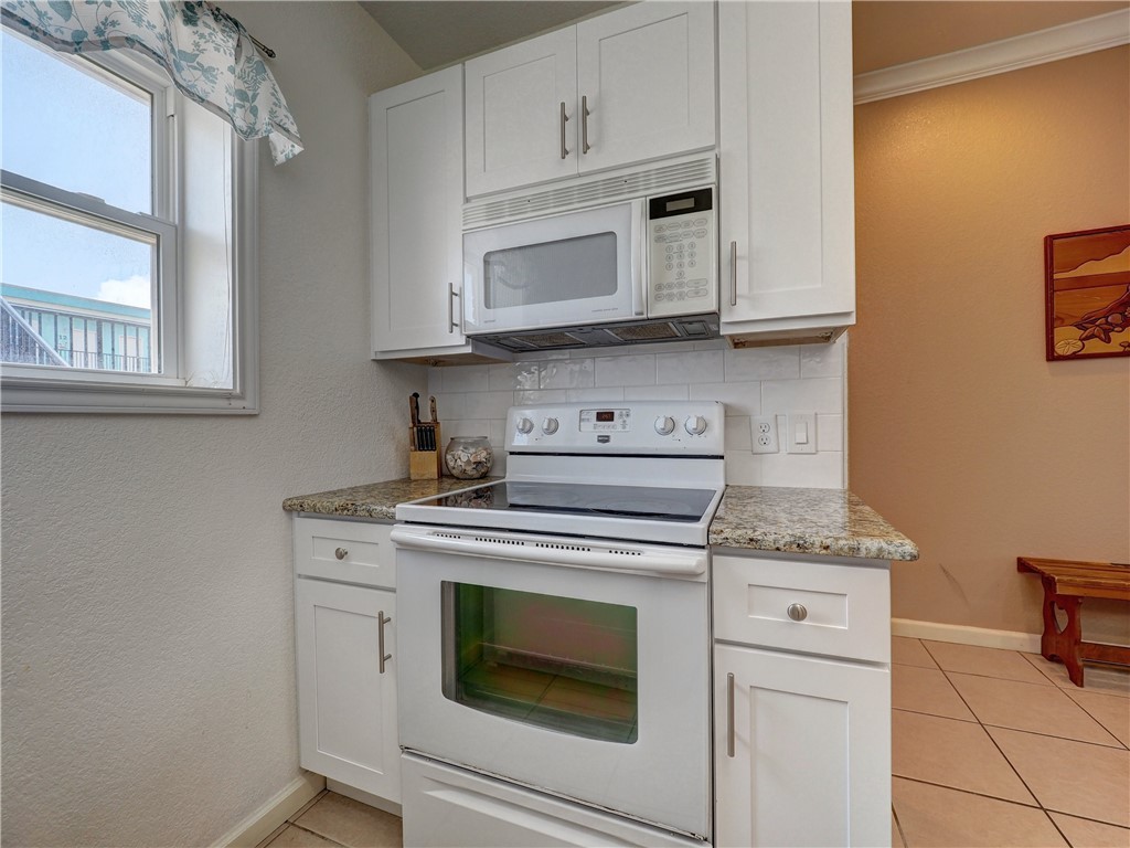 700 Island Retreat Road, Unit 37 Port Aransas, TX 78373 - Photo 9 of 34 a kitchen with granite countertop white cabinets and white appliances