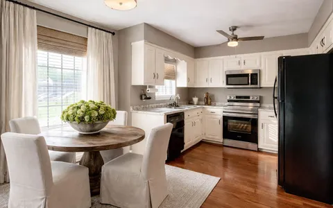 a kitchen with stainless steel appliances a stove a sink a microwave a refrigerator and white cabinets
