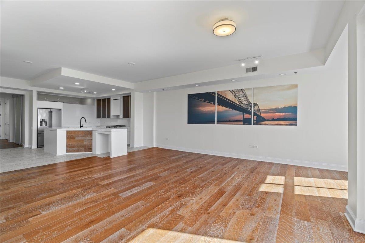 717 Riverside Drive, Unit 906 Memphis, TN 38103 - Photo 7 of 24 Unfurnished living room featuring baseboards, light wood-type flooring, a sink, and visible vents