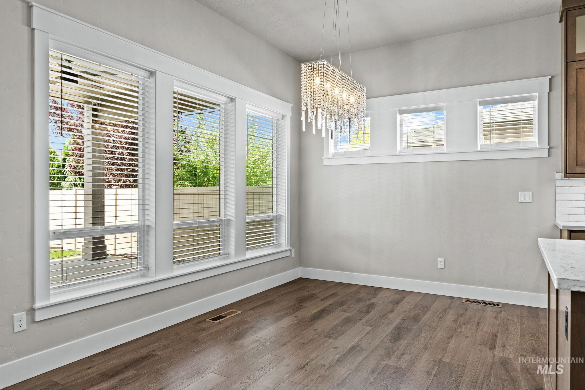 2934 East Murchison Street Meridian, ID 83642 - Photo 18 of 44 Dining area featuring wide plank wood-finish flooring, a crystal chandelier, and multiple windows with white trim
