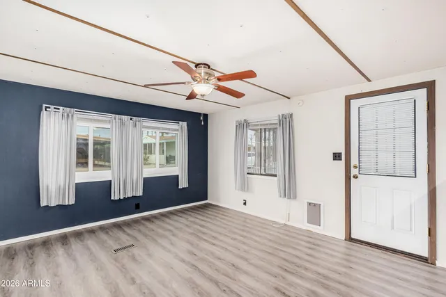 a view of an empty room with wooden floor and a window