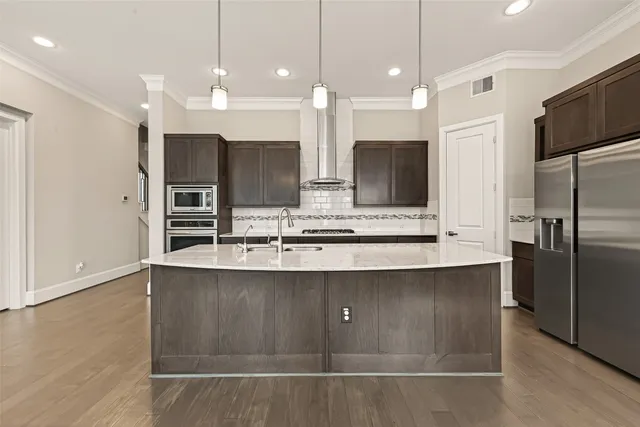a large kitchen with a large counter top stainless steel appliances and cabinets