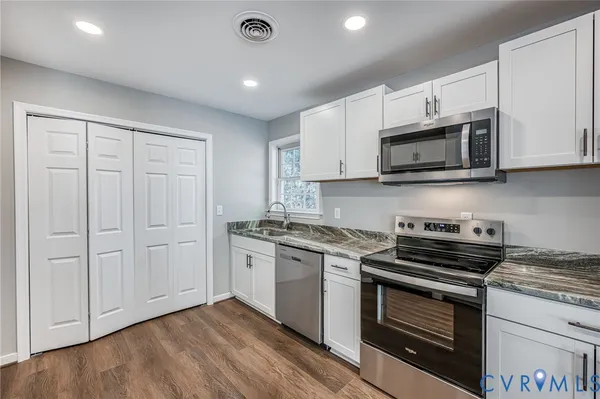 a kitchen with granite countertop cabinets stainless steel appliances and wooden floor