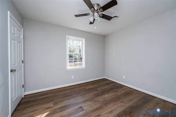 an empty room with wooden floor fan and windows