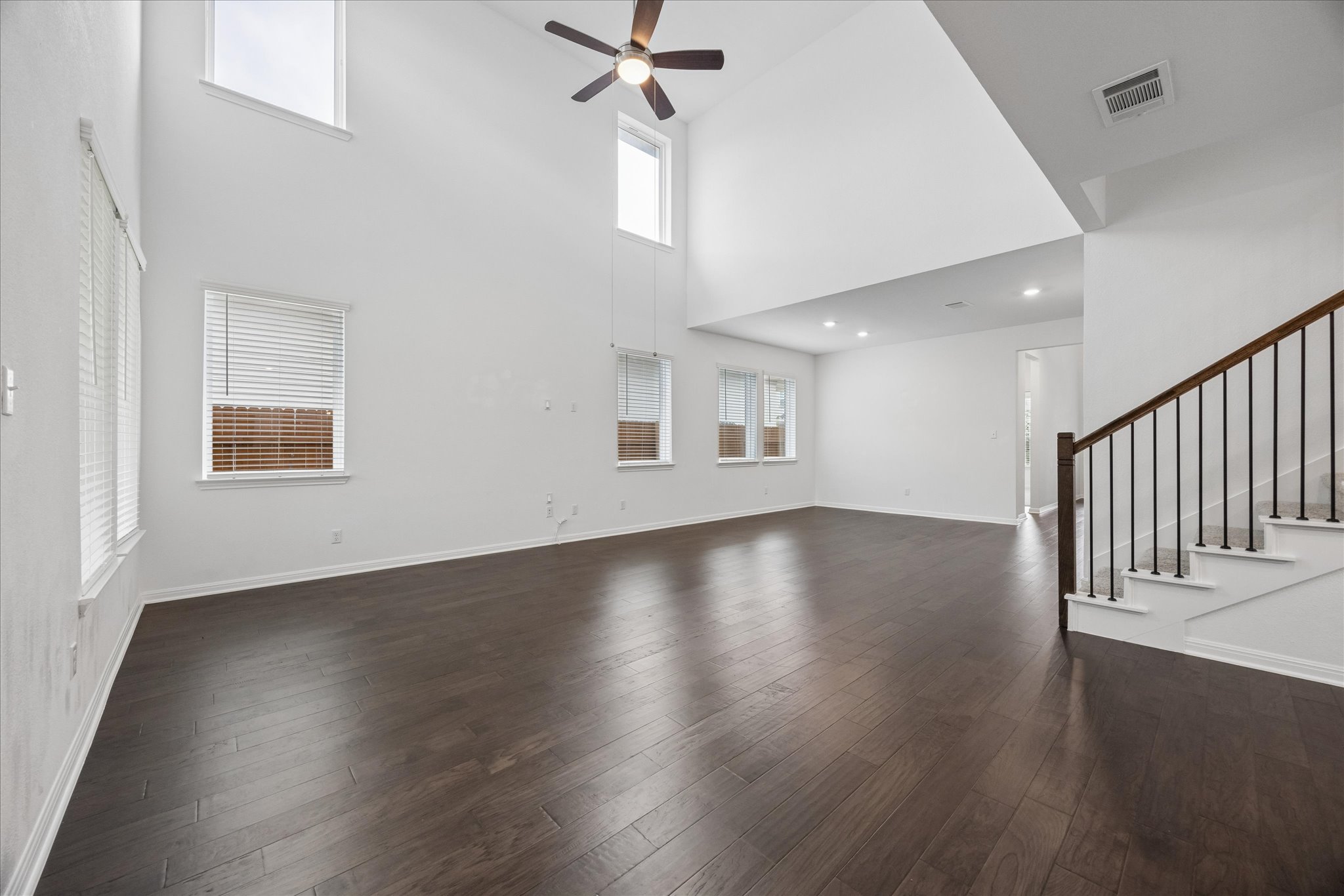 6407 Rounded Pebble Lane Buda, TX 78610 - Photo 6 of 32 A spacious, naturally illuminated living room showcasing rich hardwood floors and an elegant staircase.