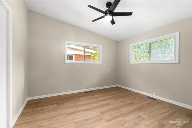 a view of empty room with wooden floor and fan