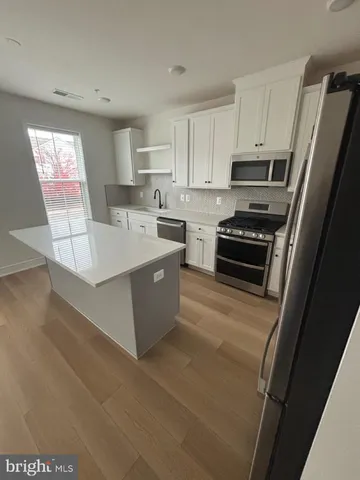 a large kitchen with stainless steel appliances a stove a refrigerator a sink a oven with white cabinets