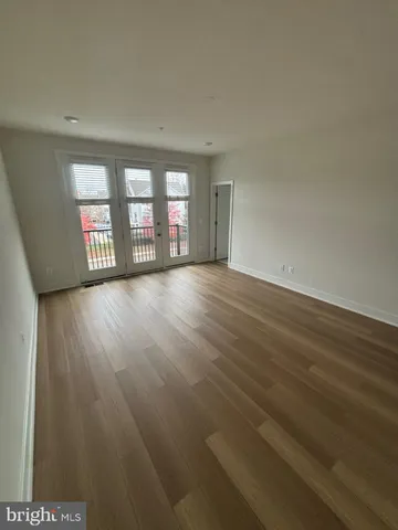 a view of an empty room with window and wooden floor