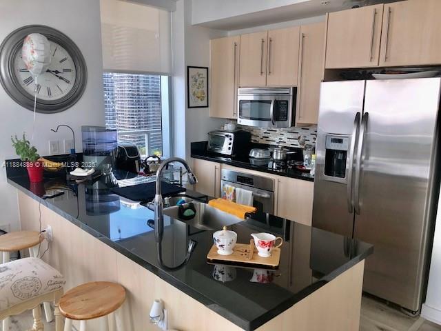 1111 Southwest 1st Avenue, Unit 3225 Miami, FL 33130 - Photo 5 of 24 a kitchen with stainless steel appliances granite countertop a refrigerator a stove and a sink with wooden floor