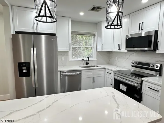 a kitchen with stainless steel appliances a kitchen island a stove a refrigerator and a sink