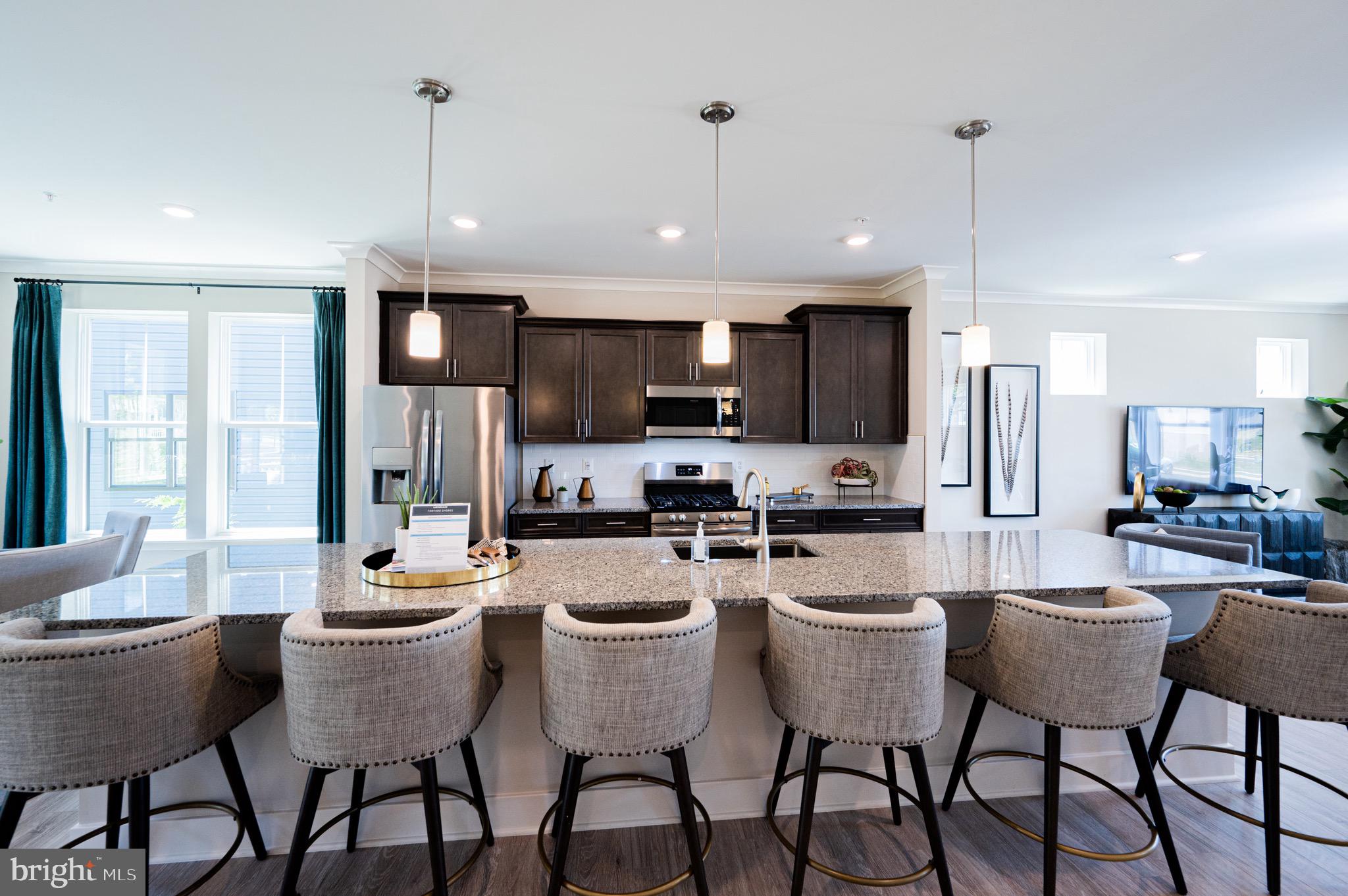 7209 Paper Way Glen Burnie, MD 21060 - Photo 14 of 40 a kitchen with stainless steel appliances kitchen island granite countertop a dining table chairs refrigerator and cabinets