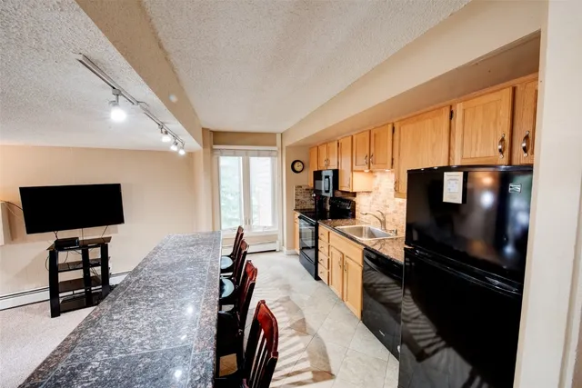 a living room with stainless steel appliances furniture a flat screen tv and a refrigerator