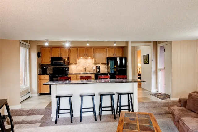 a kitchen with stainless steel appliances kitchen island granite countertop a dining table and chairs in it