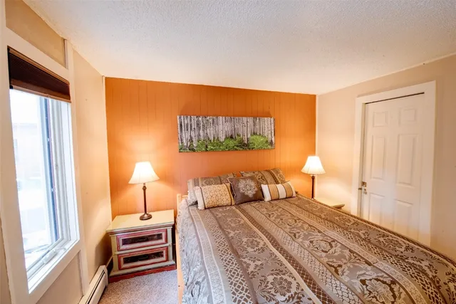 a bedroom with a bed and a lamp on dresser