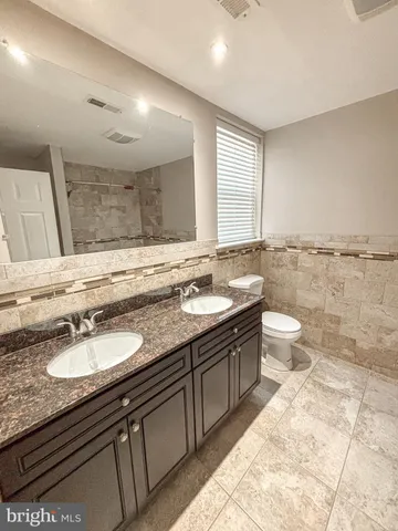 a bathroom with a granite countertop sink a toilet a mirror and a bathtub