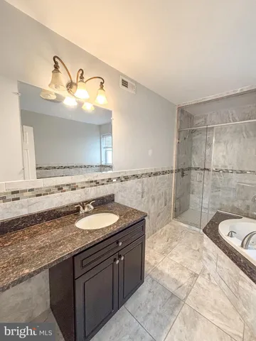 a bathroom with a granite countertop sink a mirror and bathtub