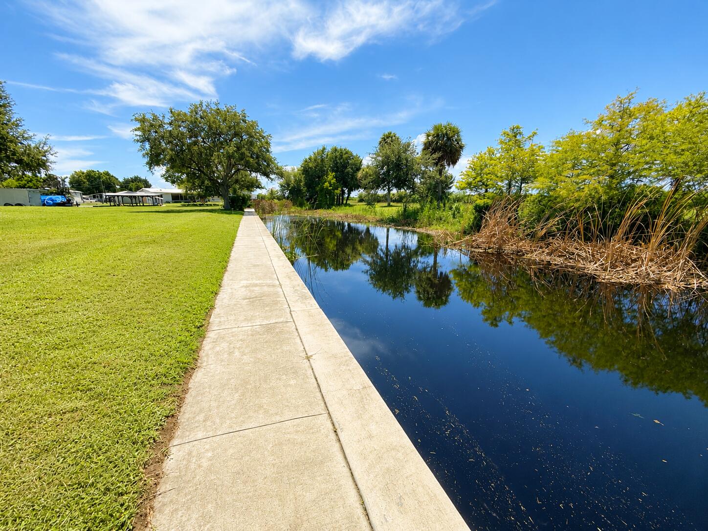 1121 Orange Loop Okeechobee, FL 34974 - Photo 33 of 33 Sunlit Walkway Beside Reflective Canal