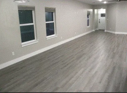a view of an empty room with wooden floor and windows