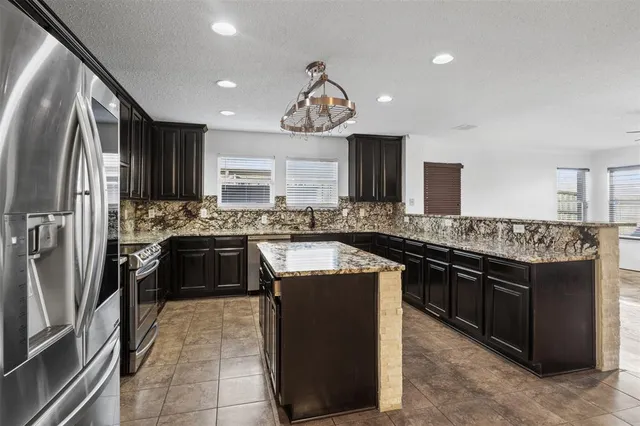 a kitchen with stainless steel appliances granite countertop a stove a sink and a refrigerator