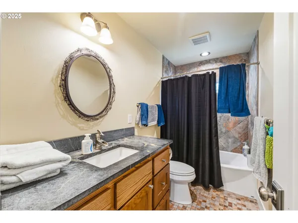 a bathroom with a granite countertop sink toilet mirror vanity and shower