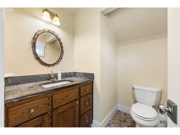 a bathroom with a toilet sink vanity granite and mirror