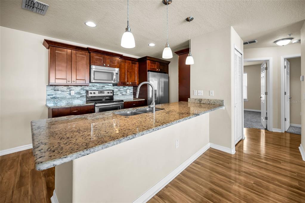 5064 Royal Palms Way, Unit 204 New Port Richey, FL 34652 - Photo 13 of 89 a large kitchen with kitchen island granite countertop a large counter top stainless steel appliances and cabinets