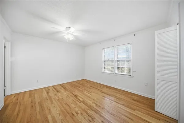 an empty room with wooden floor and windows