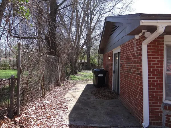 a view of a pathway of a house with backyard and wooden fence