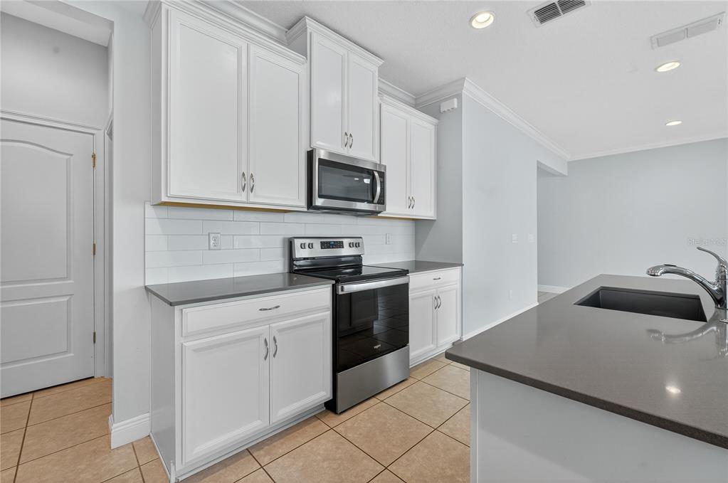6687 Alder Road Harmony, FL 34773 - Photo 13 of 42 a kitchen with white cabinets and stainless steel appliances