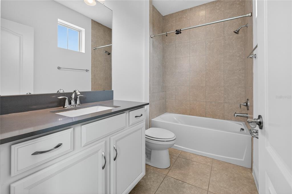 6687 Alder Road Harmony, FL 34773 - Photo 28 of 42 a bathroom with a granite countertop sink a toilet and shower