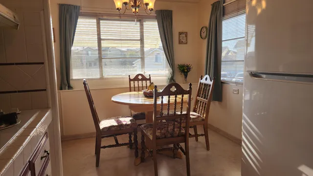 a kitchen with stainless steel appliances granite countertop a refrigerator a stove and a dining table with wooden floor