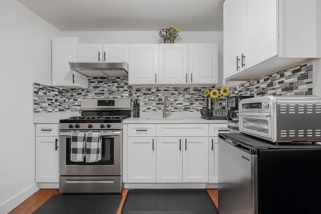a kitchen with white cabinets and appliances