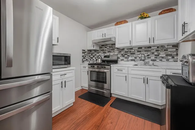 a kitchen with white cabinets and appliances