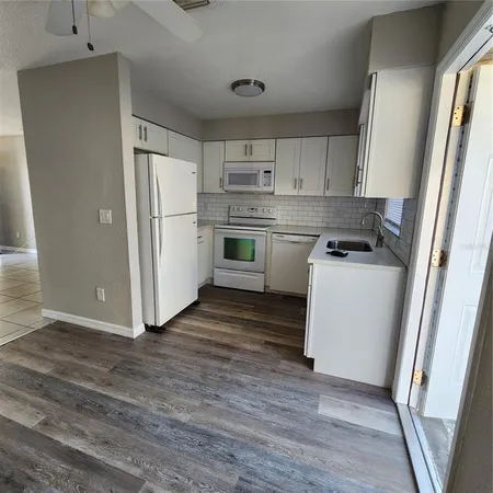 wooden floor in an empty room with a kitchen