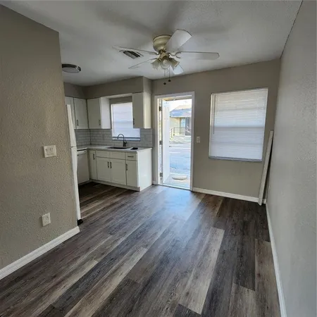 a view of kitchen and empty room with wooden floor
