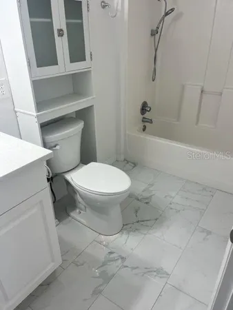 a white toilet sitting next to a bath tub and a shower