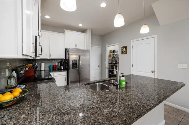 a kitchen with stainless steel appliances granite countertop a refrigerator a stove a sink a counter top space and cabinets