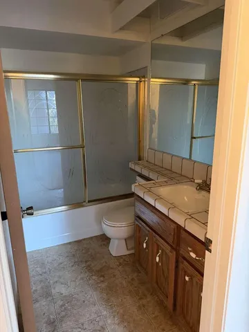 a bathroom with a granite countertop sink toilet and shower