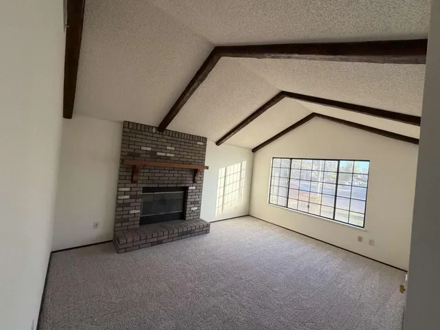 an empty room with windows and fireplace