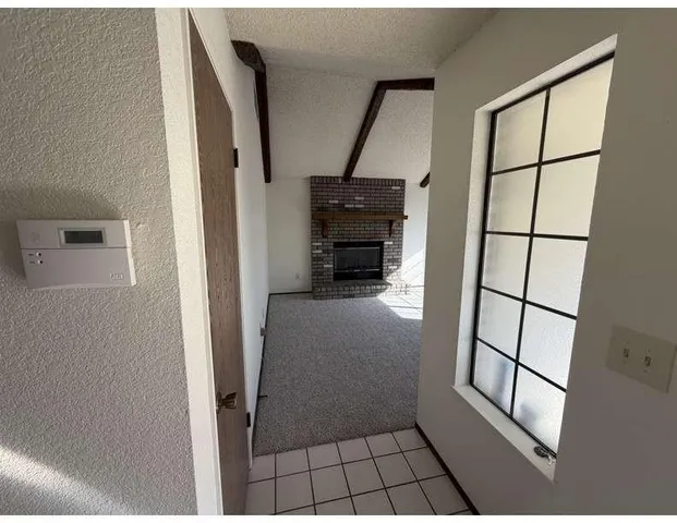 a view of an empty room with a fireplace and a window