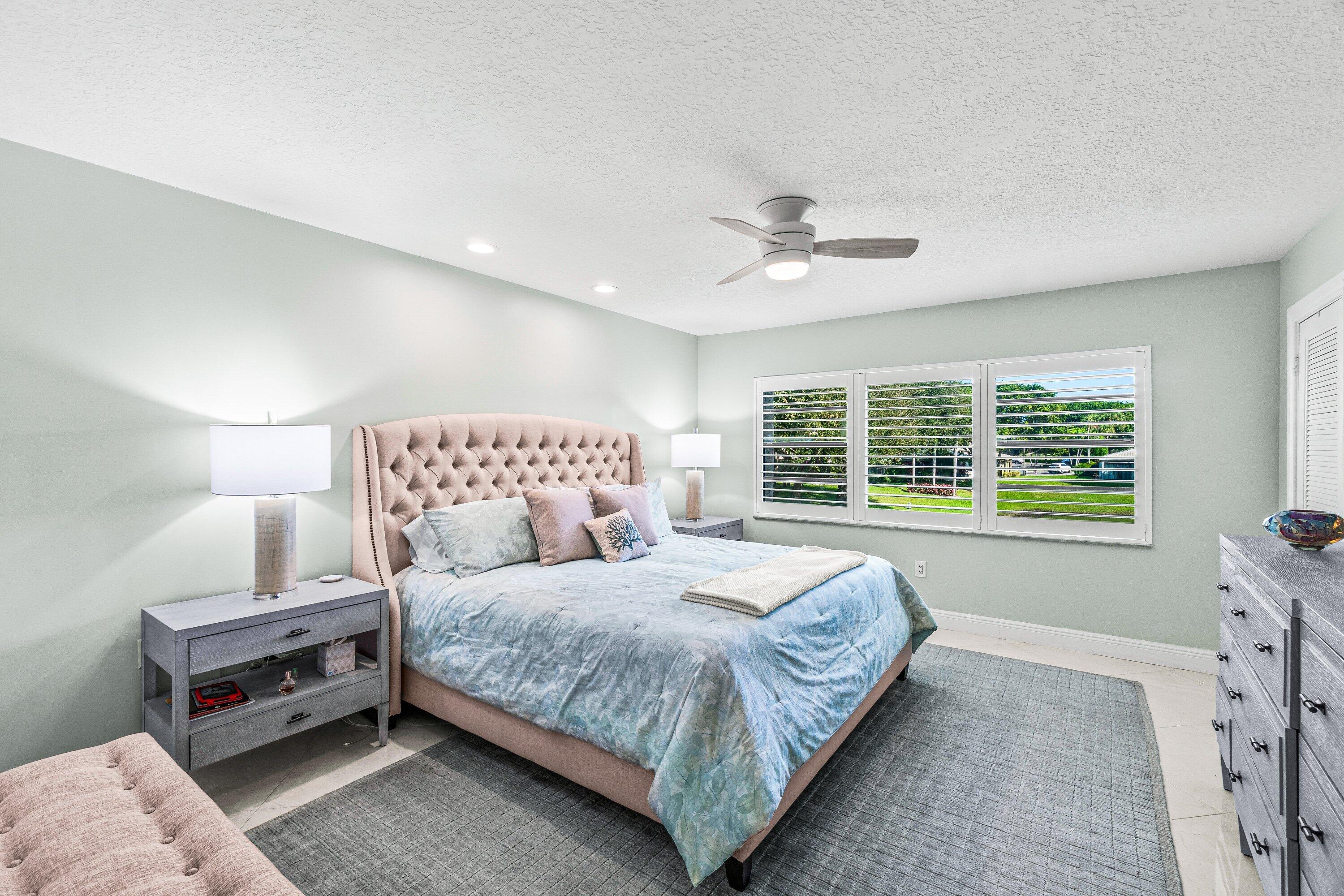 24 Stratford Drive East, Unit D Boynton Beach, FL 33436 - Photo 17 of 52 a spacious bedroom with a bed and a chandelier