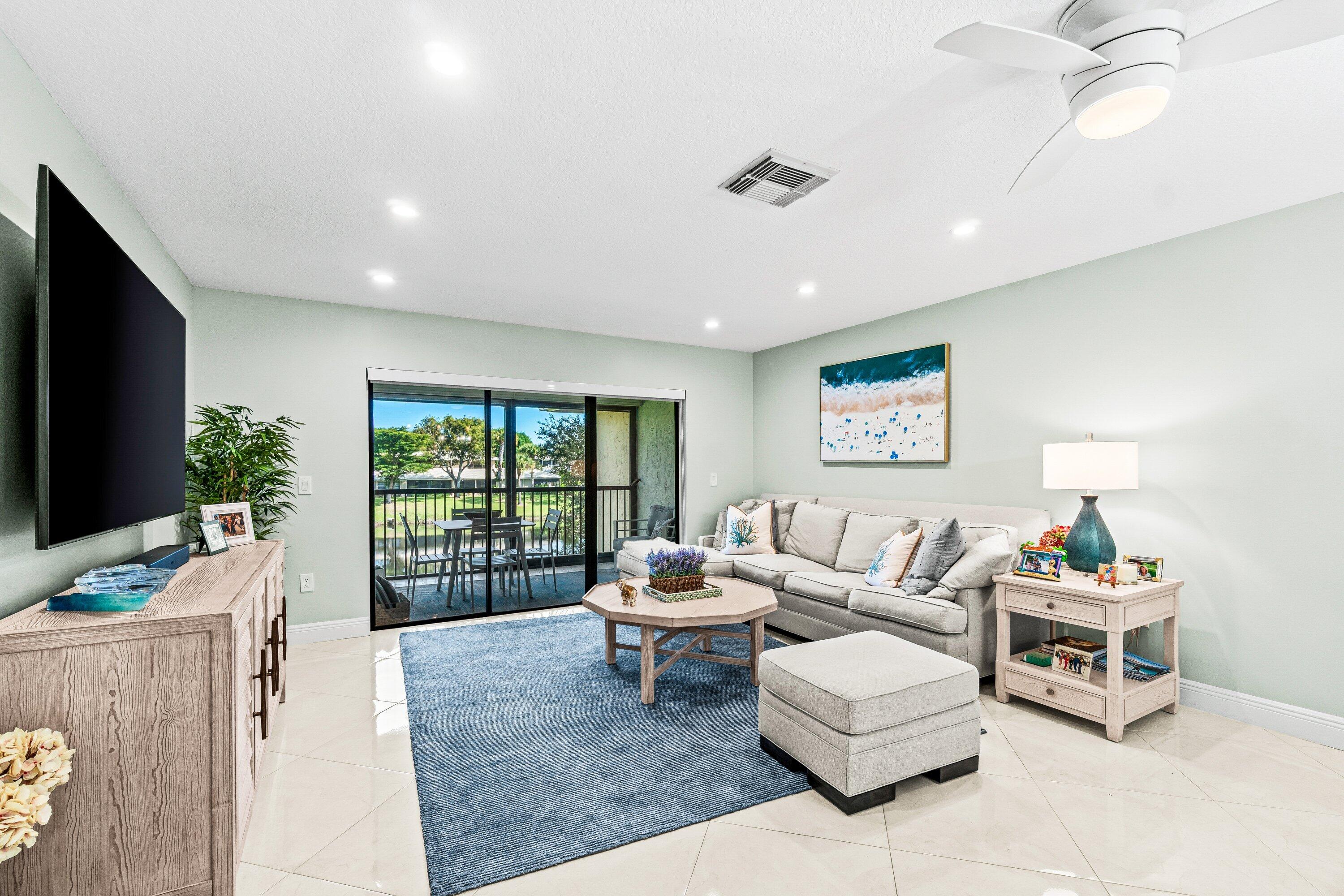 24 Stratford Drive East, Unit D Boynton Beach, FL 33436 - Photo 3 of 52 a living room with furniture a flat screen tv and a large window