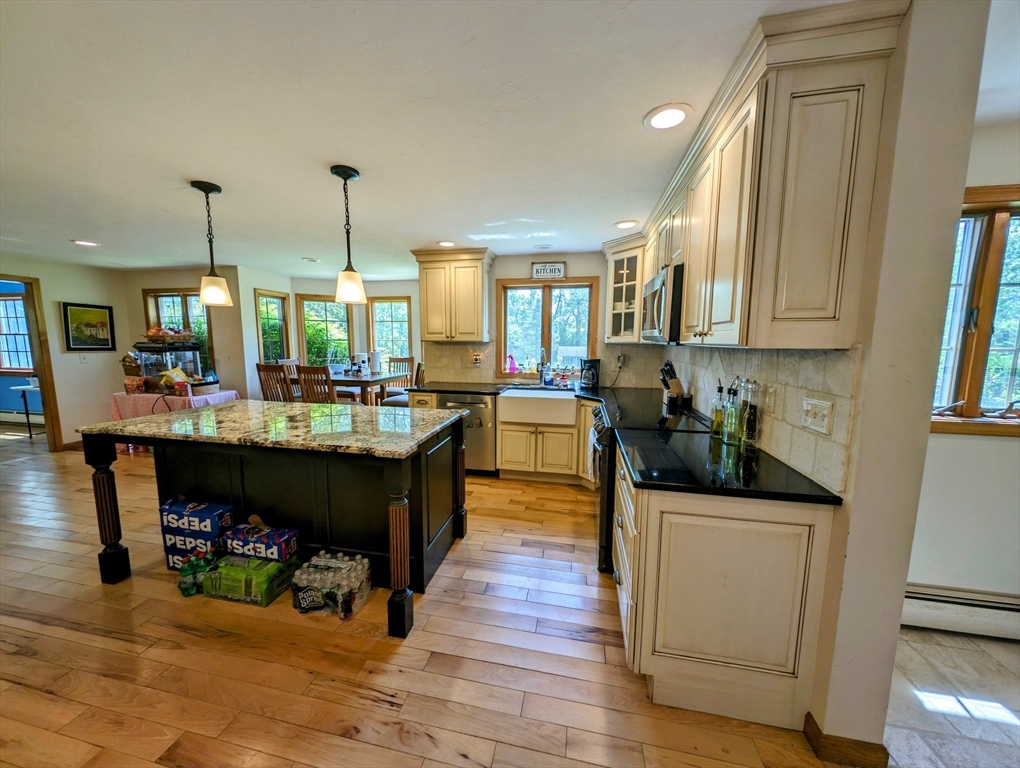 7 Robbins Road Charlton, MA 01507 - Photo 3 of 28 a kitchen with stainless steel appliances kitchen island granite countertop a sink dishwasher a stove and a dining table with wooden floor