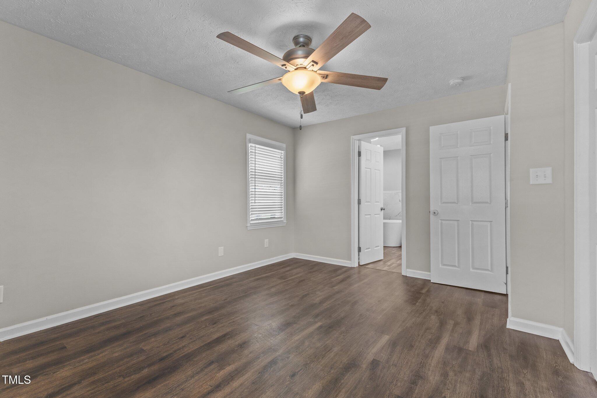 8431 Clinton Road Stedman, NC 28391 - Photo 12 of 24 an empty room with wooden floor ceiling fan and windows