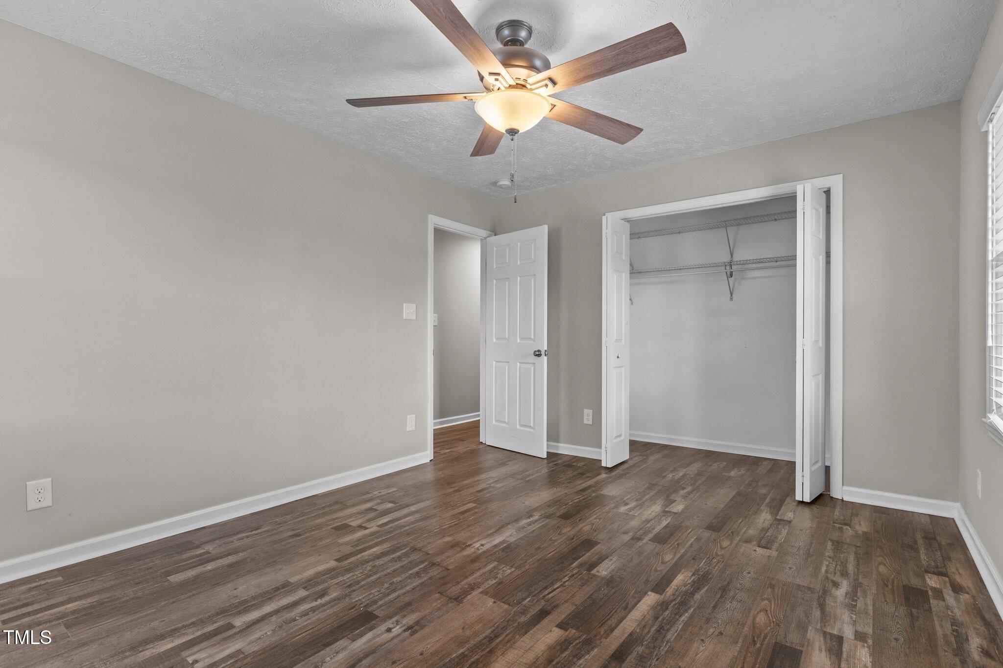 8431 Clinton Road Stedman, NC 28391 - Photo 17 of 24 a view of an empty room with window a ceiling fan and wooden floor