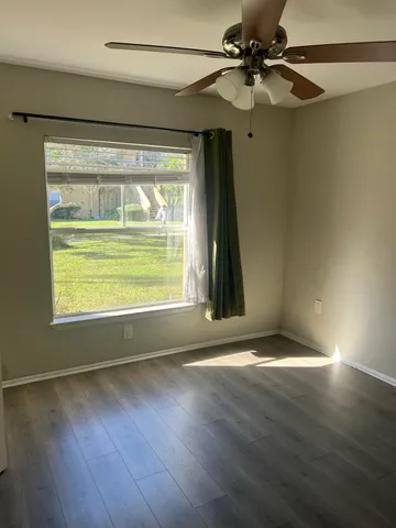 a view of an empty room with wooden floor and a window